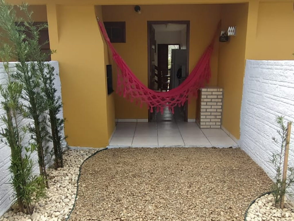 Sala com sofá em L, almofadas coloridas, tapete e televisão; atmosfera confortável para descanso