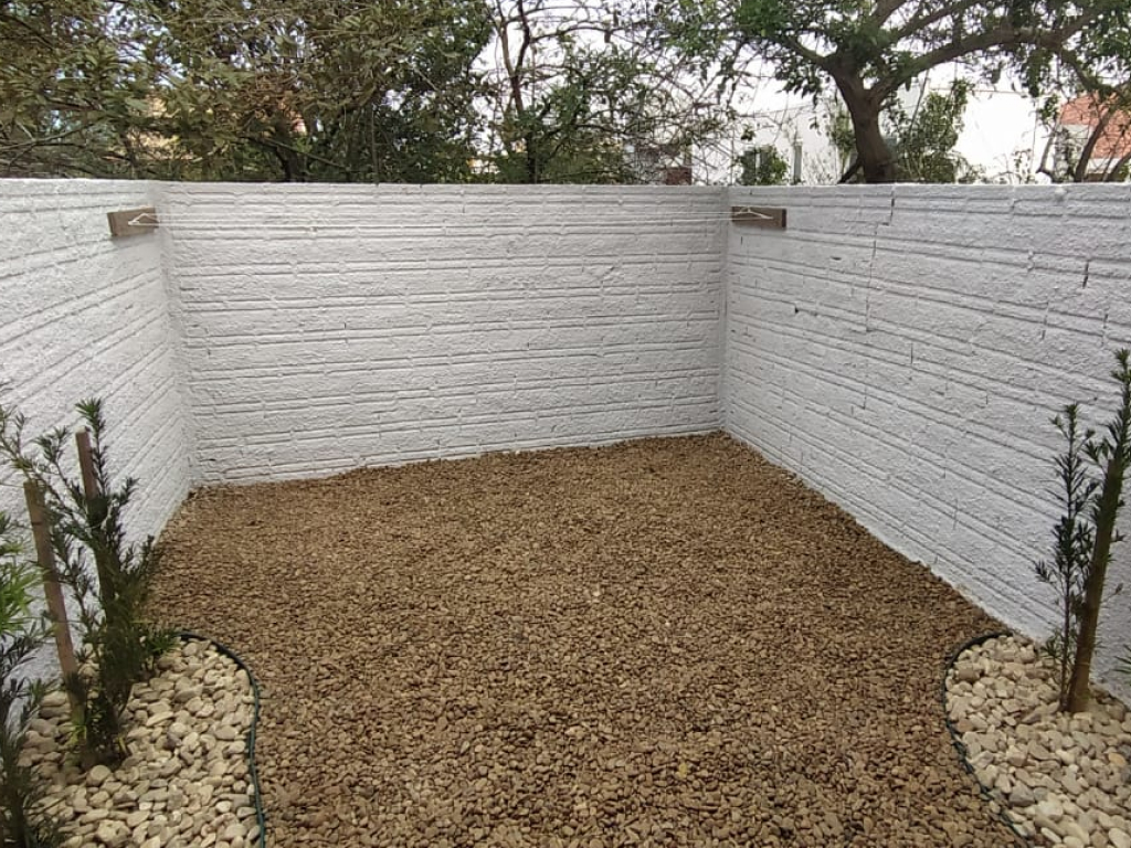 Fachada iluminada ao anoitecer com pequeno jardim frontal e portão, transmitindo sensação acolhedora e segura