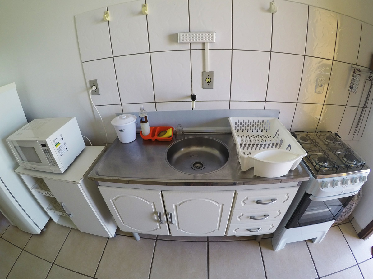 Quarto de casal com cama de casal, cabeceira, travesseiros e armário aéreo; iluminação suave e sensação de conforto