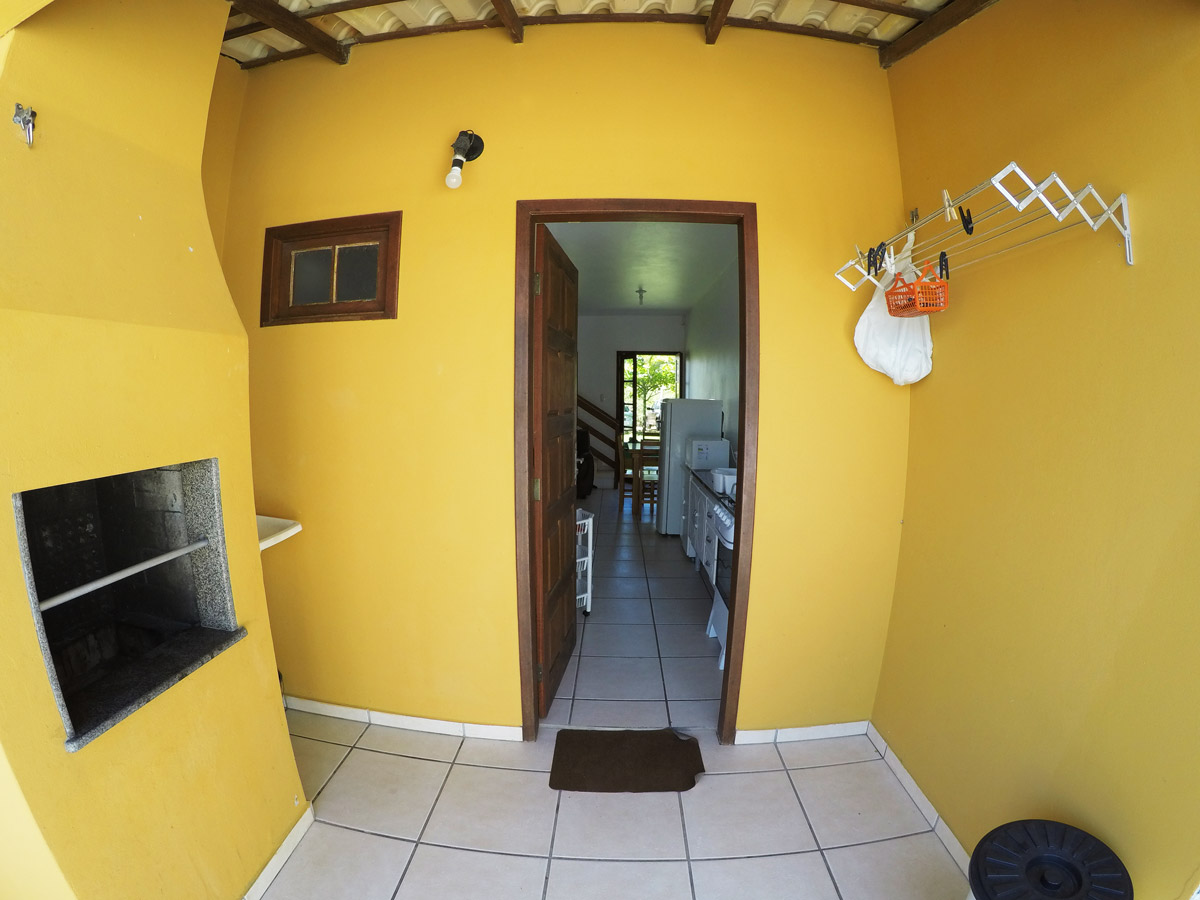 Quarto de solteiro com cama simples e cama auxiliar parcialmente puxada, prateleira e janela com cortina; ambiente organizado